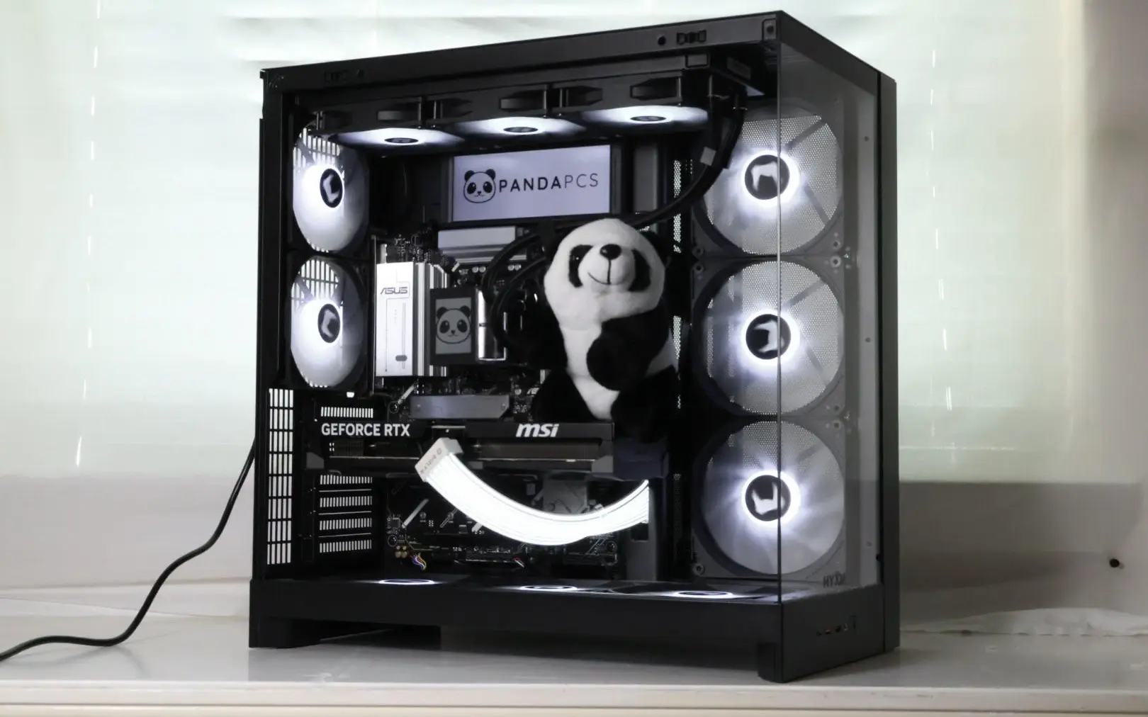 A finished PandaPCs build: black case, white RGB fans, branded display and a panda plush inside.